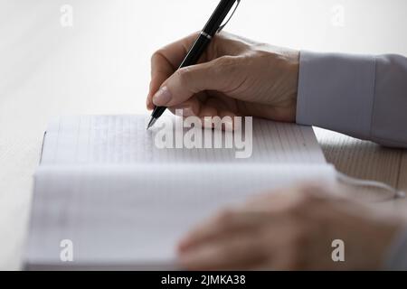 Hands of adult woman writing notes in notebook Stock Photo