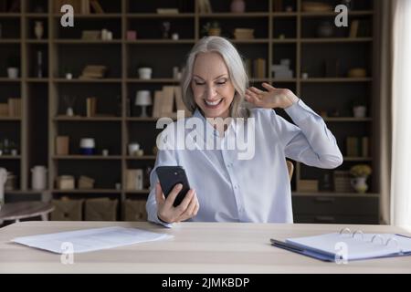 Cheerful pensioner woman talking to family on mobile phone Stock Photo