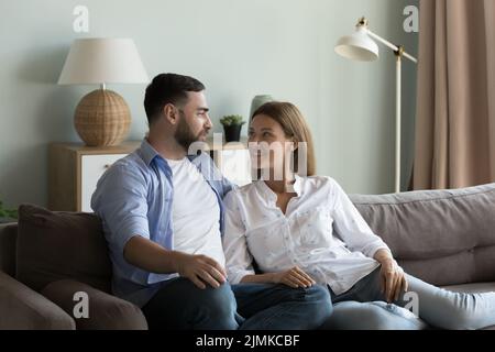 Couple relaxing on sofa talking, enjoy weekend at home Stock Photo