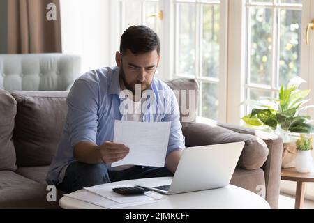 Man reading documents, examining bills doing paperwork at home Stock Photo