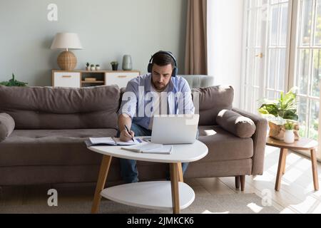 Man jotting notes use laptop working online from home Stock Photo