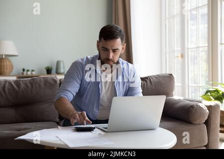 Man pay taxes, bills online using e-bank on laptop Stock Photo