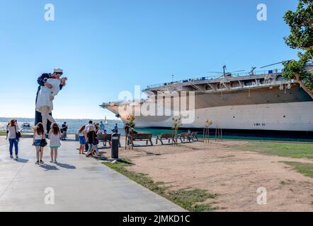 Tuna Harbor Park in San Diego, CA, with The Kissing Taylor aka Unconditionally Surrender statue and the UUS Midway Museum on the right. Stock Photo