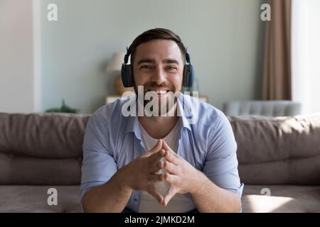 Man wear headphones looks at camera participates in on-line stream Stock Photo