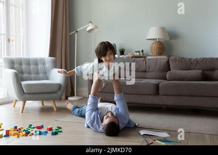 Young dad lift on stretched arms cute little son Stock Photo