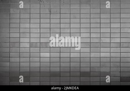 Wall made of tiles or blocks with some stains, front view. High resolution full frame textured background in black and white. Copy space. Stock Photo