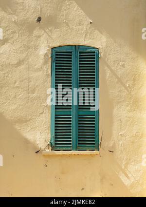 Old wooden window shutters closed against yellow wall. Stock Photo