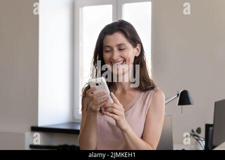 Woman office employee standing at workplace using smartphone Stock Photo