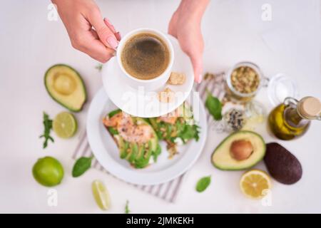 Freshly made Avocado, salmon and cream cheese toasts on a white ceramic plate Stock Photo