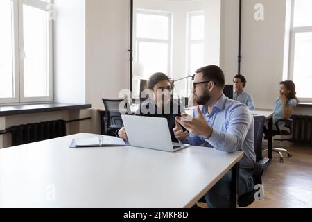 Mentor training young Indian intern, giving instructions, using laptop Stock Photo