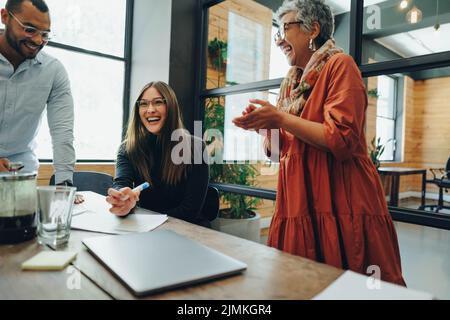 Group of successful businesspeople laughing cheerfully during an office meeting. Team of multicultural businesspeople collaborating in a creative work Stock Photo