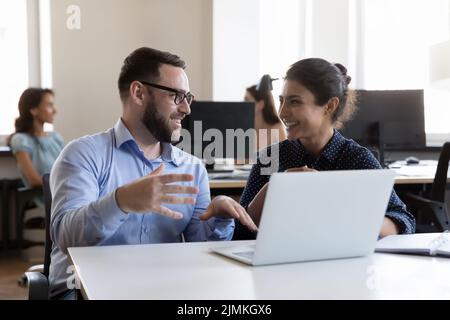 Friendly colleagues working on project sit in coworking with laptop Stock Photo