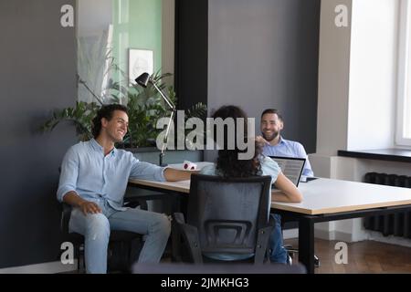 Three diverse office employees joking talking during break at workplace Stock Photo