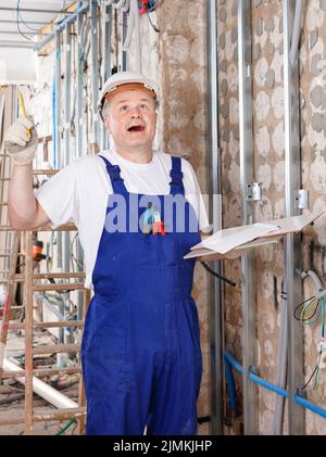 Happy contractor pointing pen up while planning building works, having good idea or smart construction solution Stock Photo