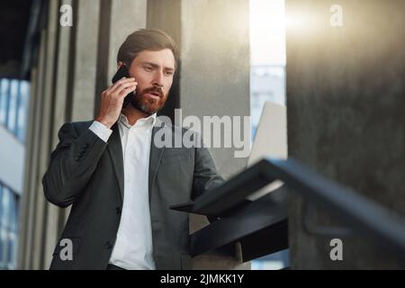 Attractive businessman talking phone standing near office building during break Stock Photo