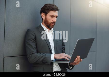 Focused Businessman working on laptop outside office building  Stock Photo