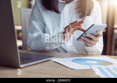 Close up of businesswoman hands using phone while sit on her workplace in office Stock Photo