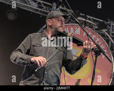 Dan Booth, violinist and fiddle player with British folk band Ferocious Dog seen performing live on stage at Wickham Festival. Ferocious Dog is a six-piece band who deals in a vibrant vein of Celtic-folk infused punk rock, comfortably slotting in between Billy Bragg and The Levellers. The band has headlined tours of the UK and Europe, performed in Kenya and Dubai, festivals such as Bearded Theory, Alchemy, Deerstock, Farmer Phil's Festival, Splendour, Lowlands (Netherlands), Glastonbury Festival and Beautiful Days among many other. Stock Photo