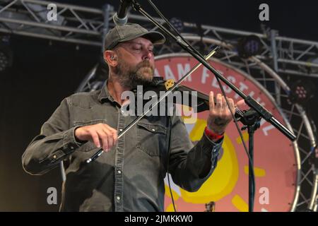 Dan Booth, violinist and fiddle player with British folk band Ferocious Dog performs live on stage at Wickham Festival. Ferocious Dog is a six-piece band who deals in a vibrant vein of Celtic-folk infused punk rock, comfortably slotting in between Billy Bragg and The Levellers. The band has headlined tours of the UK and Europe, performed in Kenya and Dubai, festivals such as Bearded Theory, Alchemy, Deerstock, Farmer Phil's Festival, Splendour, Lowlands (Netherlands), Glastonbury Festival and Beautiful Days among many other. Stock Photo