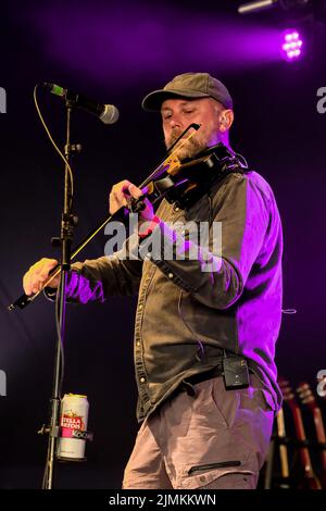 Dan Booth, violinist and fiddle player with British folk band Ferocious Dog seen performing live on stage at Wickham Festival. Ferocious Dog is a six-piece band who deals in a vibrant vein of Celtic-folk infused punk rock, comfortably slotting in between Billy Bragg and The Levellers. The band has headlined tours of the UK and Europe, performed in Kenya and Dubai, festivals such as Bearded Theory, Alchemy, Deerstock, Farmer Phil's Festival, Splendour, Lowlands (Netherlands), Glastonbury Festival and Beautiful Days among many other. Stock Photo