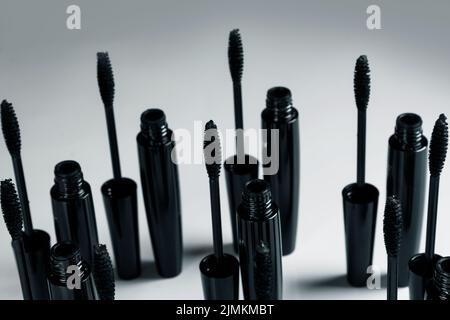 Black mascara brushes and containers on gray background Stock Photo