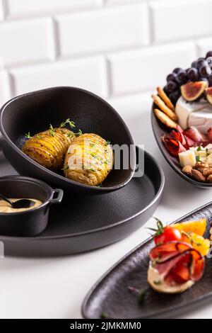 Dinner with grilled potato and assorted cheese, prosciutto and fruits, bruschetta on a plate Stock Photo