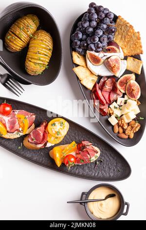 Dinner with grilled potato and assorted cheese, prosciutto and fruits, bruschetta on a plate Stock Photo