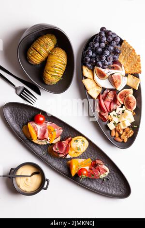 Dinner with grilled potato and assorted cheese, prosciutto and fruits, bruschetta on a plate Stock Photo