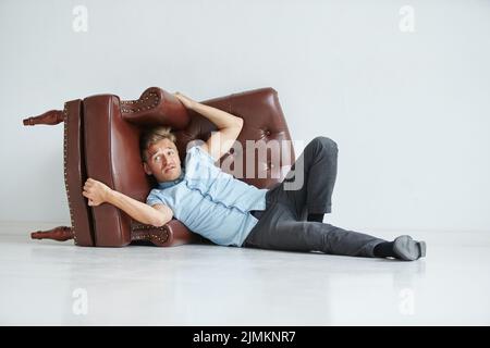 Brutal man in a shirt with short sleeves sitting in the chair, his fists clenched, slightly bent, under the gaze of the forehead Stock Photo