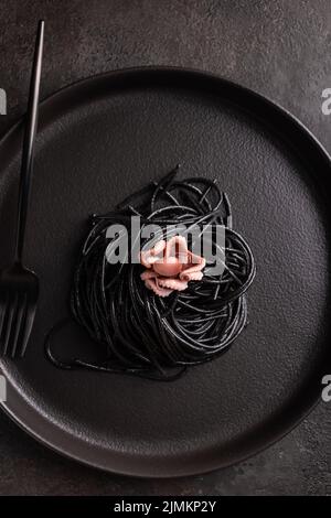 Black spaghetti with cuttlefish ink with boiled octopus Stock Photo - Alamy