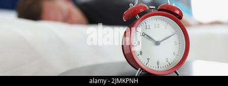A red alarm clock stands on table in the bedroom Stock Photo