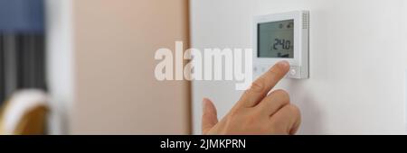 Hand sets a programmable thermostat for heating and cooling Stock Photo