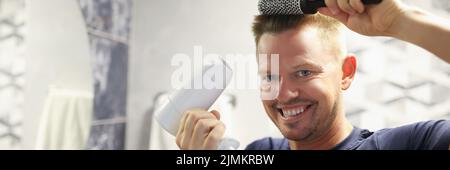 Happy man doing his own blow-drying at home Stock Photo