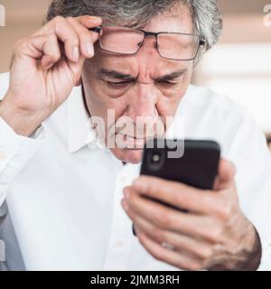 Close up serious senior man looking smart phone Stock Photo