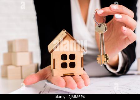 Woman holding set keys with wooden house Stock Photo