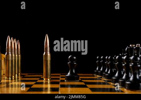 Chessboard on a black background, blank for design. Rifle cartridges instead of white pieces on the chessboard. Old, cracked chess with cartridges and Stock Photo
