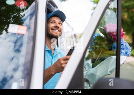 Courier inside the white van during flowers delivery is waiting for a client Stock Photo
