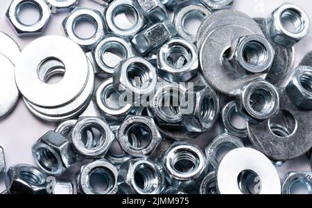 Metal nuts and washers for bolts isolated on white. Nuts for bolts close-up. Metal objects in close-up. Stock Photo
