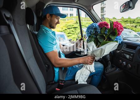 Courier inside the white van during flowers delivery Stock Photo
