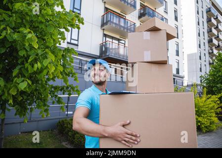 Strong delivery man holding a stack of a cardboard boxes Stock Photo