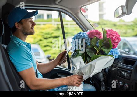 Courier inside the white van during flowers delivery Stock Photo