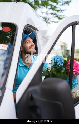 Courier inside the white van during flowers delivery is waiting for a client Stock Photo