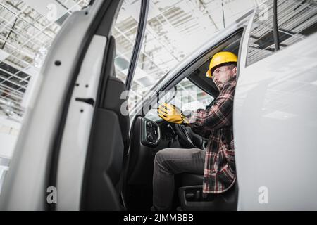 Caucasian Building Supervisor at His 30s Getting Off the Van at the Construction Site Inside the Large Hall Wearing the Safety Helmet. Ready and Deter Stock Photo