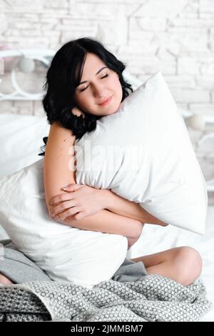 Smiling woman hugs her pillow close-up Stock Photo