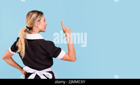 Rear view woman pointing upwards standing against blue background Stock Photo