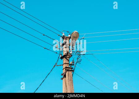 Electric wires hanging on a pole with a lighting lamp photographed from ...