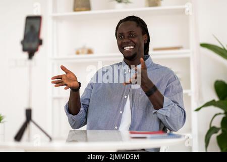 Online Coaching. Happy Black Man Recording Video Content With Smartphone At Home Stock Photo