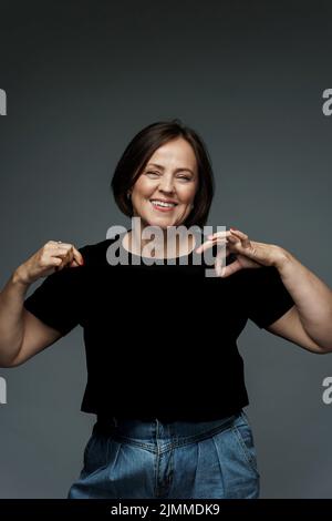 Positive middle aged woman wearing black t-shirt with empty space Stock Photo