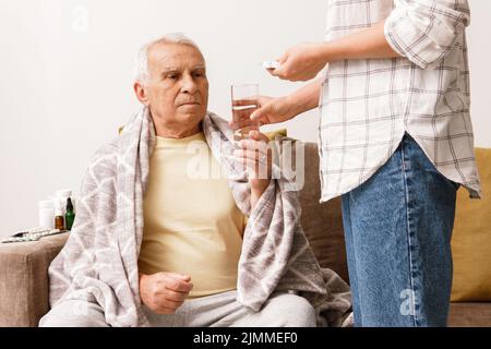 Woman is giving medicine to her sick elderly grandfather Stock Photo