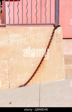 Chain links at the bottom of a railing near the concrete wall in San Francisco, California. There is a wall with rust stains from the chains below the Stock Photo